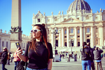 Rome,Italy, Vatican City, Rome, Saint Peter's Basilica in St. Peter's Square  Young beautiful woman  using a mobile phone taking a pictures.Concept of Italian gastronomy and travel