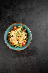 Top view of a quinoa salad with grilled chicken, cherry tomatoes, and mixed greens, served in a turquoise ceramic bowl
