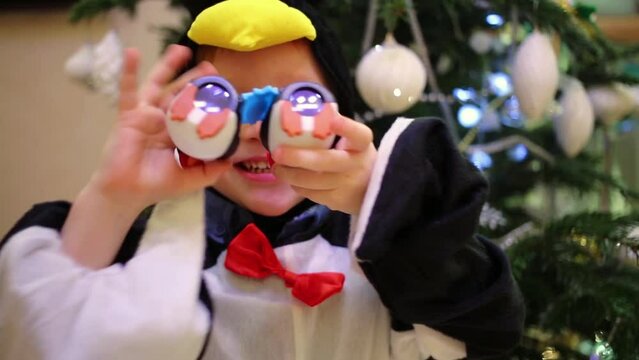 Little boy in a penguin costume are looking to toys binocular 