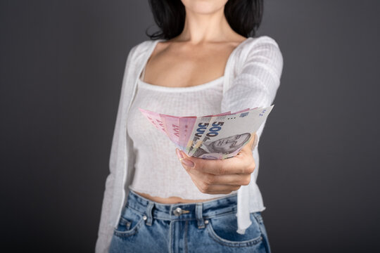 a woman gives a donation out a currency bancnote cash UAH Ukrainian hryvnia. Woman holds Fan of hryvnia. Ukraine finance concept.