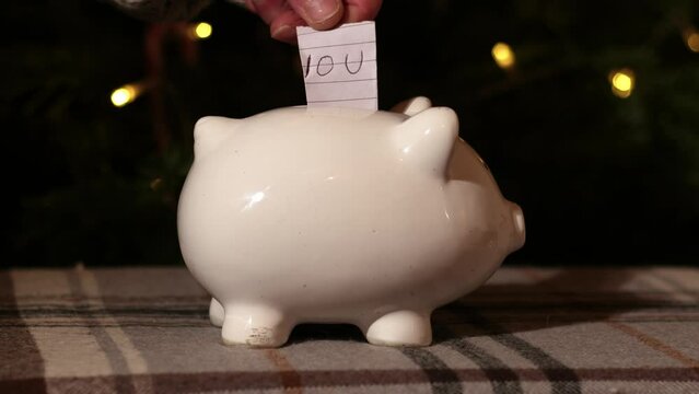Putting IOU into piggy bank savings in Christmas tree background