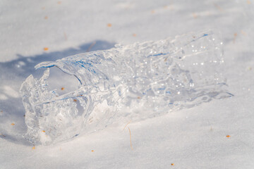 Icicle lies on white snow. The texture of snow and frozen ice. Close-up, copy space, space for text