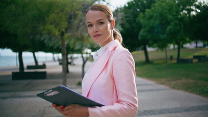 Fototapeta premium Closeup happy businesswoman posing in green city park with documents folder.