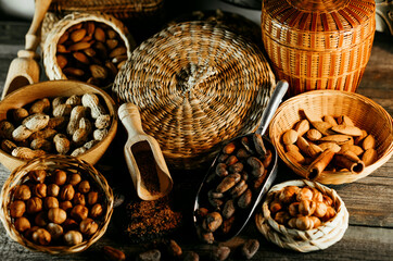 Wood scoops with almods almond between handmade wicker baskets and wood plates with almonds, hazelnut, walnut. Vintage food background with different nuts and baskets.