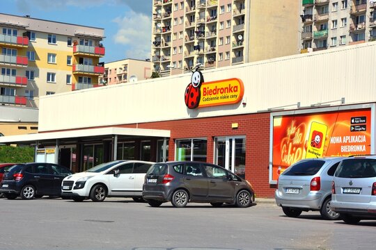 Kielce, Świętokrzyskie, Poland - 2022-06-07 - Biedronka hypermarket with parked cars near the store and apartment buildings in the background