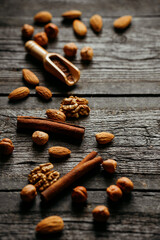 Chocolate, cinnamon, almonds, walnuts and hazelnuts on wood table. Verical background