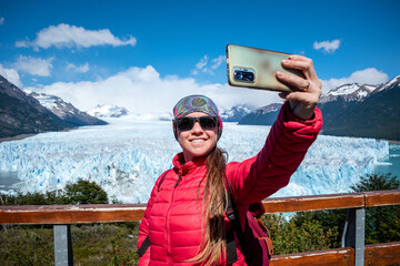 Mujer turista tomándose una selfie desde los miradores del Glaciar Perito Moreno, en la Patagonia Argentina - obrazy, fototapety, plakaty