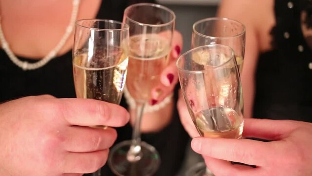 Hands of four friends clink glasses with white wine
