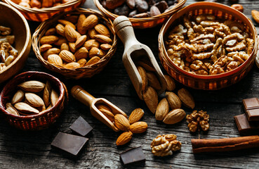 Wood scoops with almods almond between handmade wicker baskets and wood plates with almonds, hazelnut, walnut. Vintage food background with different nuts and baskets.