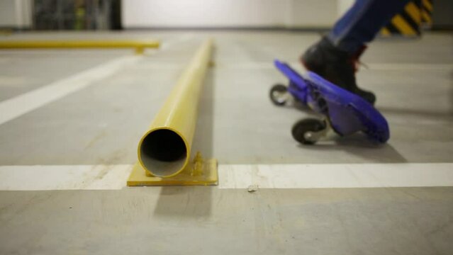 Legs of boy riding on waveboard near pipe in underground parking