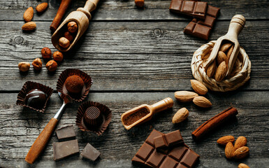 Square frame from handmade candies, two truffles, cocoa powder, chocolate and other. Sweet delicious things on old wood background