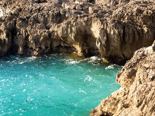 Natural background of a deserted small lagoon full of turquoise water surrounded by coastal cliffs