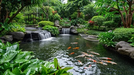 Tuinposter  a pond filled with lots of water surrounded by lush green plants and a bunch of koi fish swimming on top of a small waterfall in the middle of the pond. © Jevjenijs