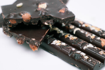 Tasty chocolate with nuts. Chocolate pieces with nuts on white background. Selective focus.