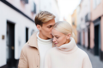 Two young lovers sharing a kiss in a pastel-colored quaint alley, showcasing a moment of affection with a blurred historic town setting. Young and modern people on Valentine's Day