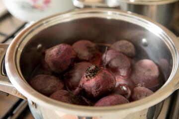 Red beets are cooked in a stainless steel pot.