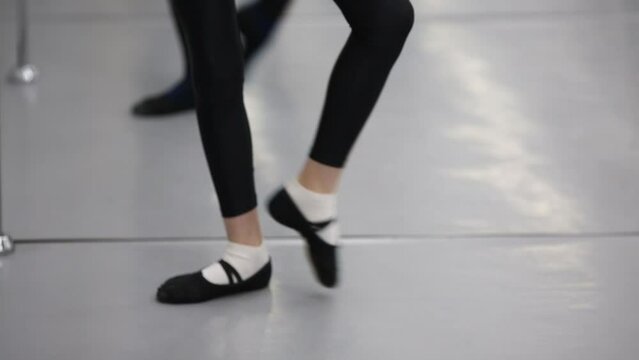 Little girls in black leggings are training at the ballet class.
