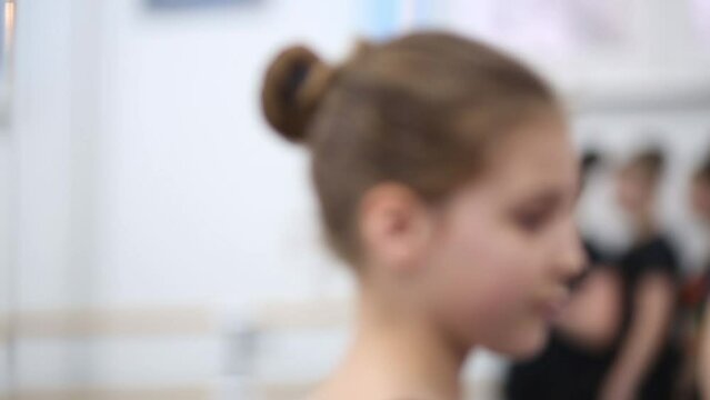 Little girl in a black leotard is whirling at the ballet class.