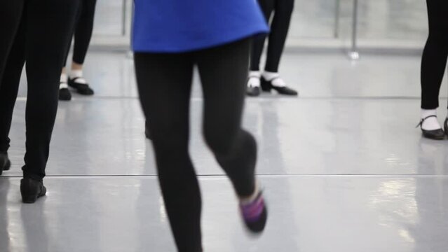 Girls are training steps one after another at the ballet class.