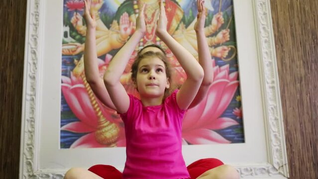 Woman and girl do exercises of yoga as multi-armed god in gym