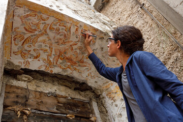 Adult Woman Restorer work with a Scalpel Cleaning Residues of Additional Plasters over Baroque Wall Painting in an Expertise Renovation Process of Cultural Heritage