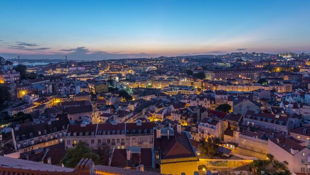 Lisbon after sunset aerial panoramic view of city centre with roofs at autumn day to night transition timelapse, Portugal. Top view from Sophia de Mello Breyner Andresen viewpoint. Lights turning on