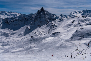 Naklejka na ściany i meble Breathtaking view to the mountains at the Courchevel ski resort in France. Active winter vacation, skiers and snowboarders going down the slopes.