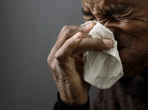 cold and flu blowing nose after catching the flu with grey black background with people stock image stock photo	