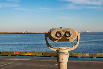 Boston, MA, US-December 8, 2023: Public viewing binoculars looking out onto Boston Harbor and Logan...