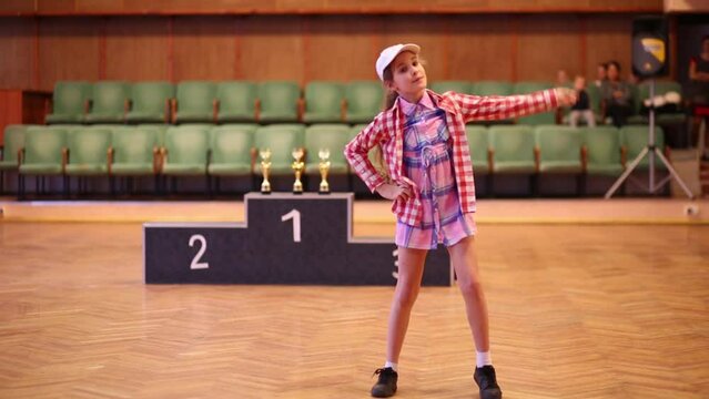 Little girl in a plaid shirt participate in dance competitions