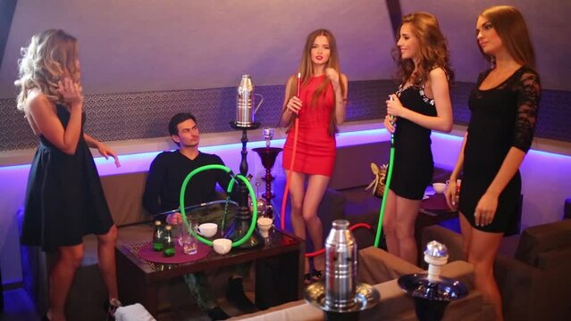 Four girls dancing and a young man and smoking hookah