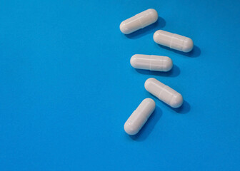 Close up white pills of medicine over blue background with copy space. Health care and medicine concept. Copy space.