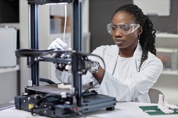 Medium close up shot of African American woman technician in protective glasses adjusting filament...
