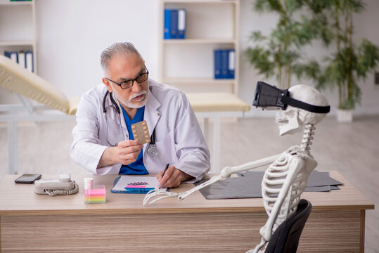 Old male doctor examining skeleton in the clinic - Powered by Adobe