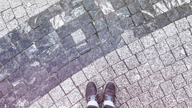 POV boots standing on cobbled pavement color grey and beige. Travel and explore historic city. Minimal wallpaper for travelers. Soft focus. film grain pixel texture. Defocused.
