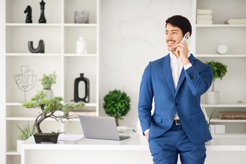 The Hispanic businessman enjoys a light-hearted moment during a phone call, his expression one of...