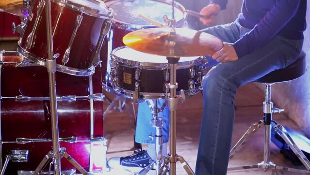 Man plays on drums in studio with light equipment during survey