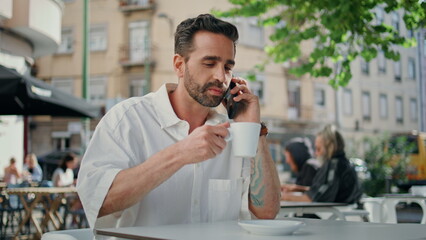 Smiling employee calling mobile phone coffeehouse close up. Man sipping espresso