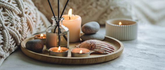 Apartment natural aroma diffusor with sea breeze fragrance. Burning candles on bamboo tray, cozy home atmosphere. Relaxation, detention zone in the living or bedroom. Stones as decor. Banner