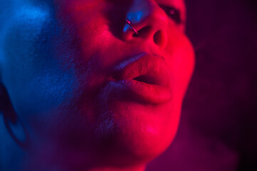 Asian woman with short haircut smoking in neon light. close-up portrait. 