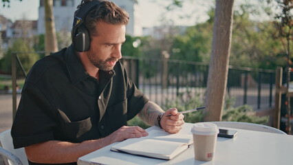 Adult student listening headphones webinar studying street cafe alone close up