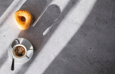 Fototapeta na wymiar An appetizing donut next to a cup of coffee, bathed in natural light, top view