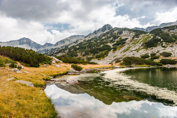 Muratovo lake bank in autumn. Pirin mountains reflecting in the clear water. Pirin national park, Bulgaria.