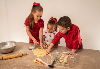 Niños preparando galletas disfrutando y aprendiendo como cocinar pequeños chef cocinando y cortando con moldes y con utensilios - obrazy, fototapety, plakaty