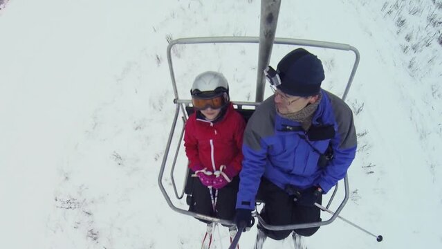 Man with girl makes selfie on cableway in ski resort, top view
