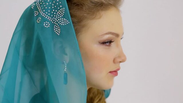 Beautiful young woman turns head with earring and hood