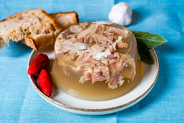 Jelly with meat, beef aspic, traditional dish. portion on plate. Bread and chili.