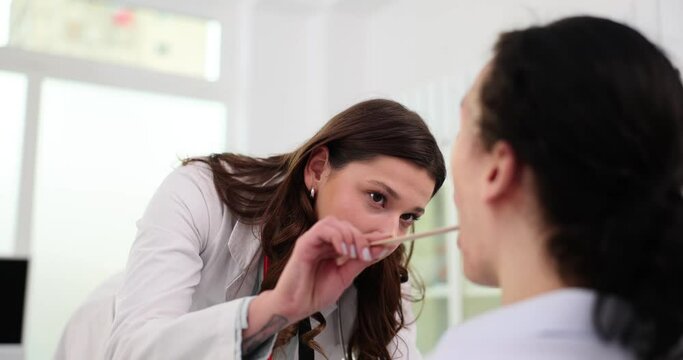 ENT clinic patient at doctor specialist otolaryngologist examines throat of young man