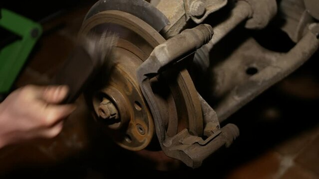 A mechanic cleans the brake pads of a passenger car from rust. Video filming in an amateur car service close-up.