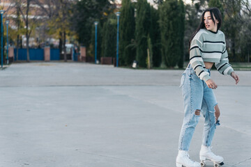 Side View of a Woman Roller Skating backwards in a Concrete Skate Park. Shot of a woman looking back while roller skating.